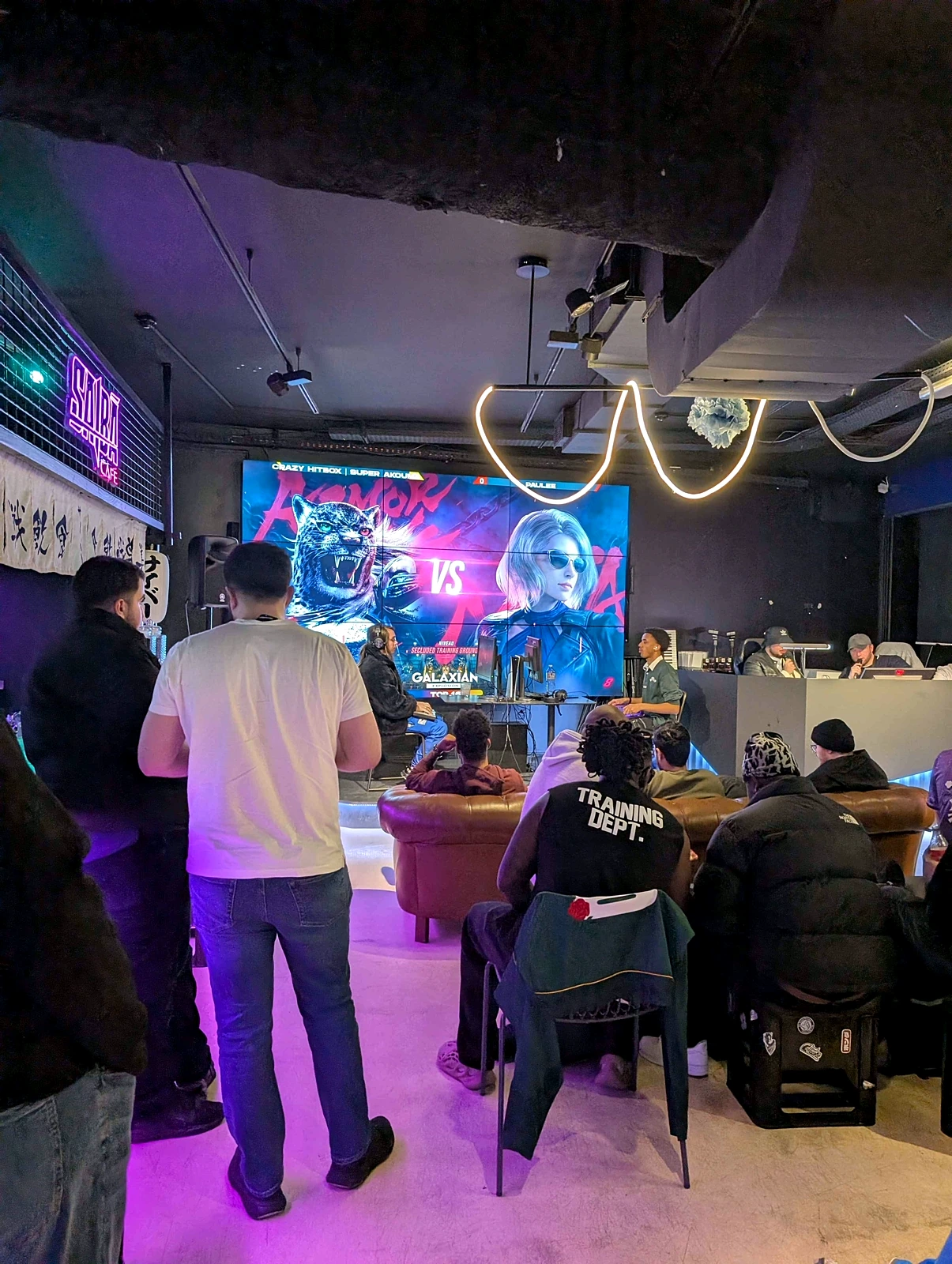 Ambiance néon du tournoi Galaxian avec écran VS géant